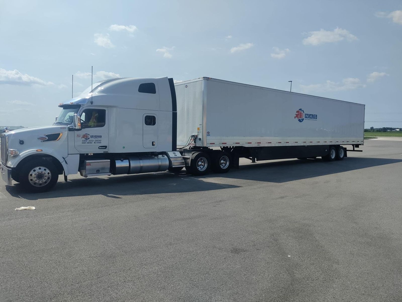 White semi-truck with NAS logo on trailer parked in a sunny lot.