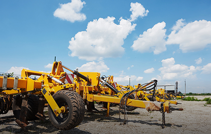 Yellow agricultural machinery under a blue sky with clouds on a sunny day