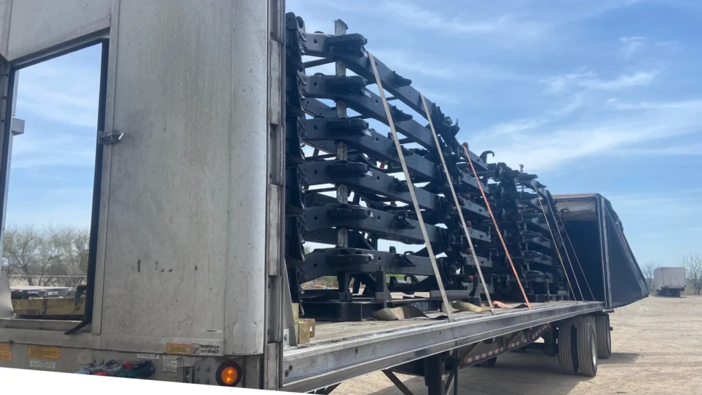 Stacked steel frames on a flatbed trailer under a clear blue sky, ready for transportation.