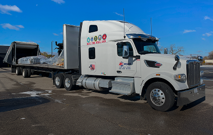 White semi-truck with flatbed trailer transporting goods on a clear day.