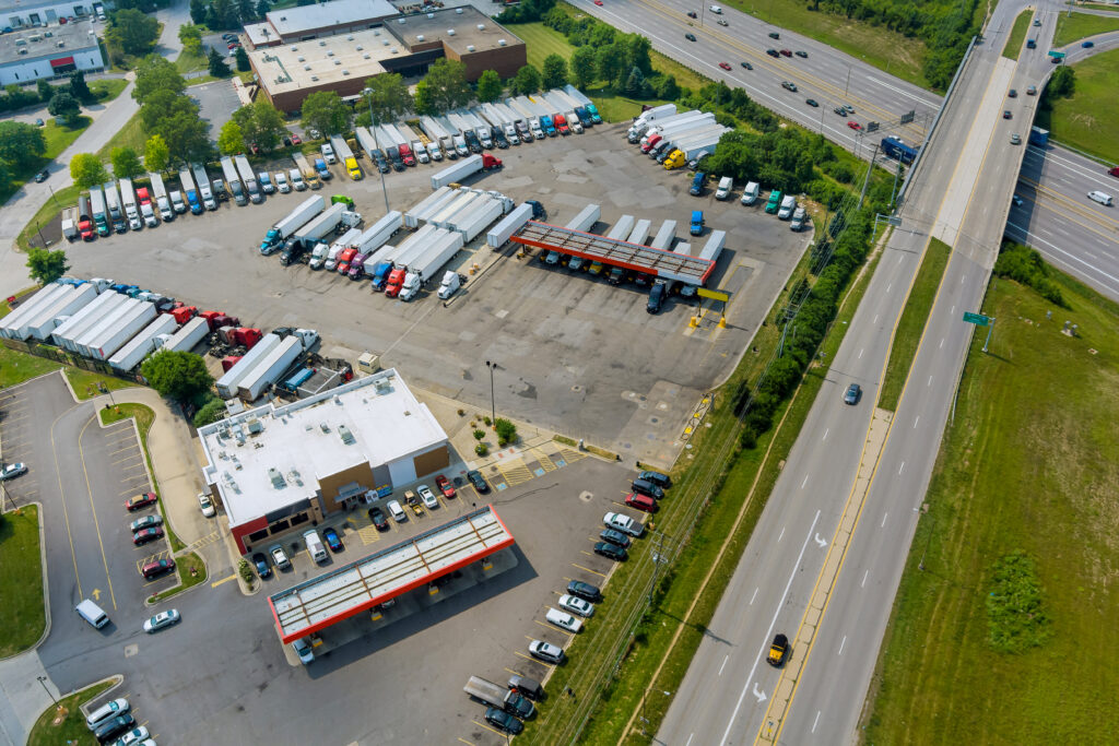 A drone shot of trucks at a rest stop with a gas station for refueling