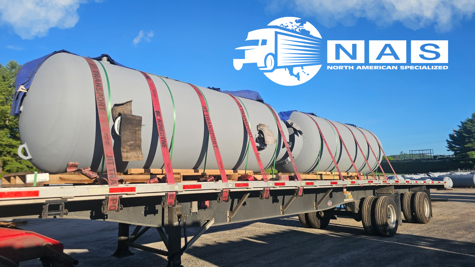 Large cooling and thermal storage tanks secured on a flatbed for specialized transportation.